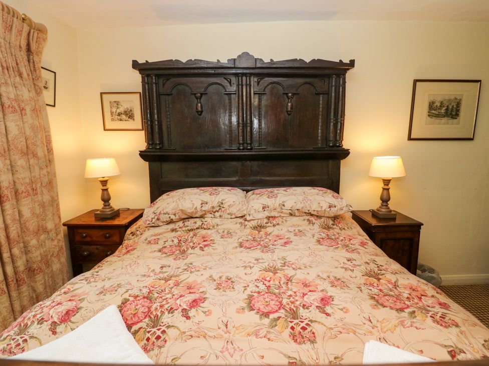 A bedroom with a bed and nightstand at The Laundrymaid's Cottage in Cartmel