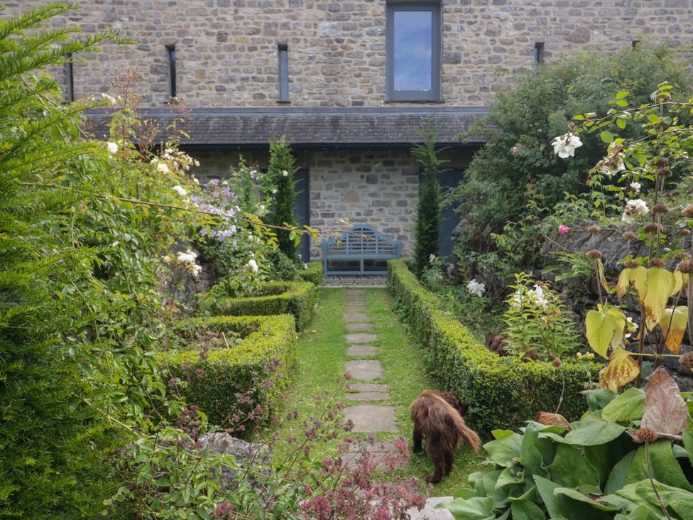 A garden with plants and a path at The Laundrymaid's Cottage in Cartmel