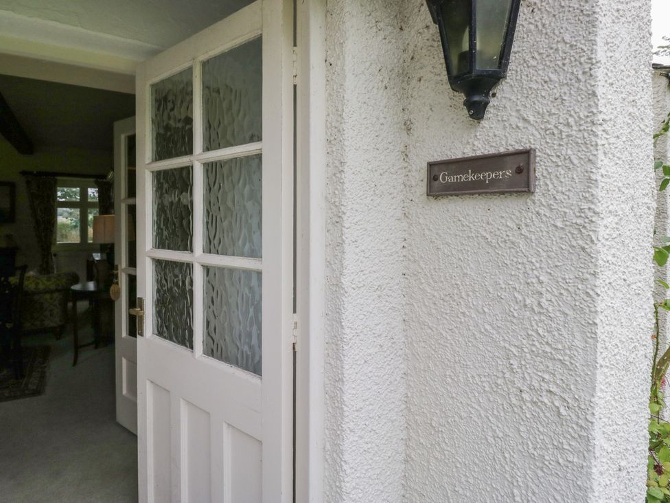 An entrance door with a sign and lamp at The Gameskeepers Cottage in Cartmel