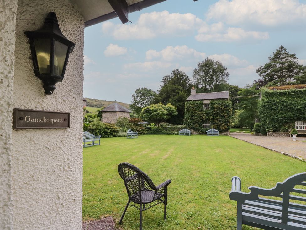 A garden with a bench and a house at The Gameskeepers Cottage in Cartmel