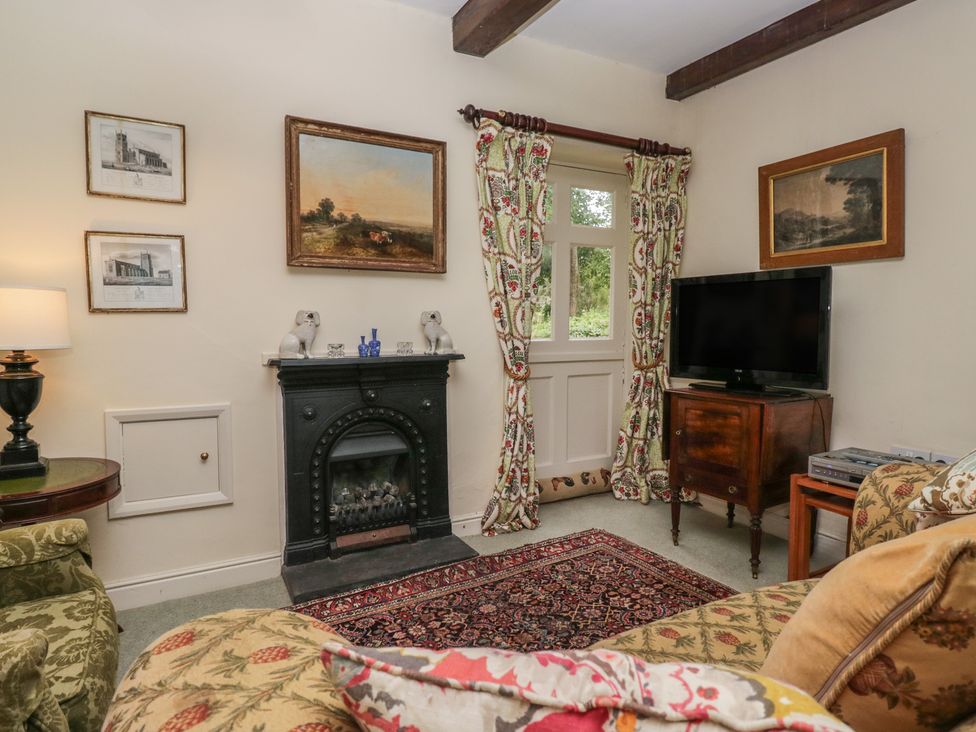 A living room with a fireplace and television at The Gameskeepers Cottage in Cartmel
