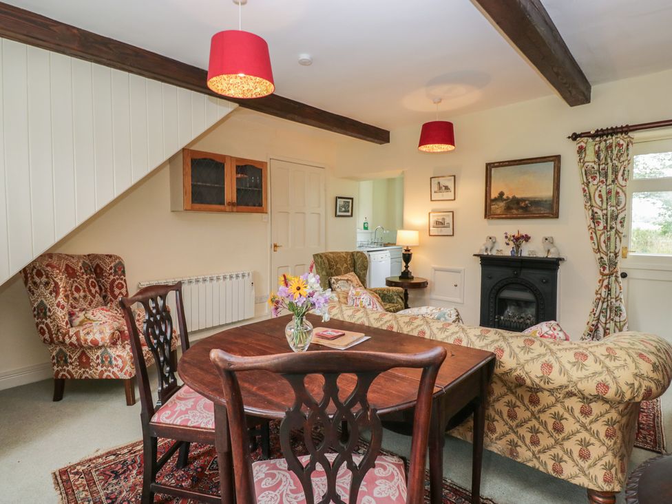 A living room with a table, chairs, and a sofa at The Gameskeepers Cottage in Cartmel