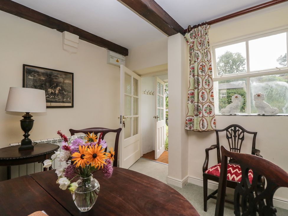 A dining room with a table and flowers at The Gameskeepers Cottage in Cartmel