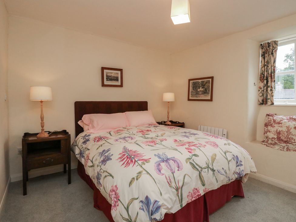 A bedroom with a bed and bedside lamps at The Gameskeepers Cottage in Cartmel
