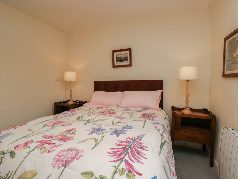 A bedroom with a bed and bedside table at The Gameskeepers Cottage in Cartmel