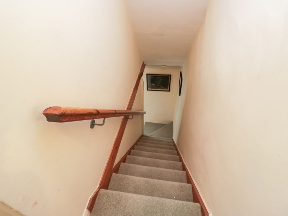 A staircase with a handrail and carpet at The Gameskeepers Cottage in Cartmel