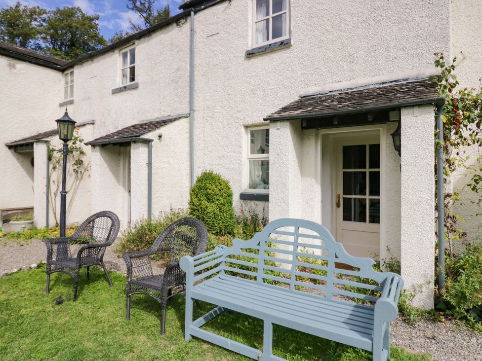 A bench and chairs in front of a house at The Gameskeepers Cottage in Cartmel