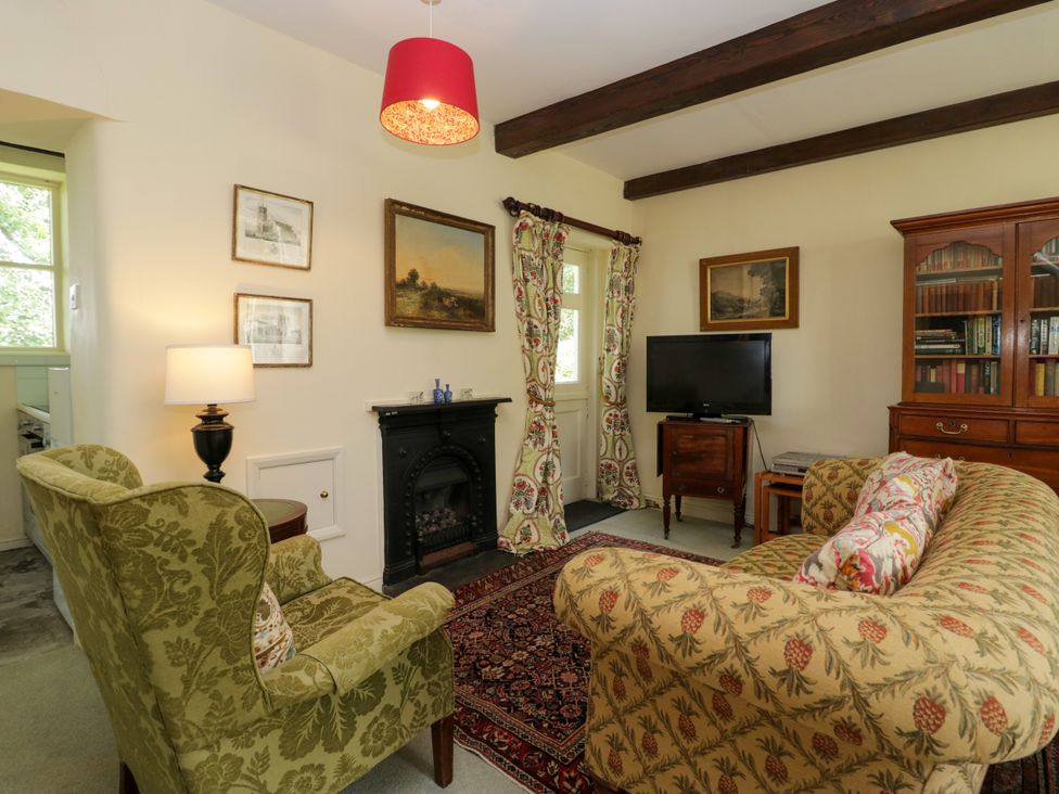 A living room with a sofa and a television at The Gameskeepers Cottage in Cartmel