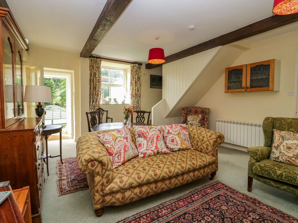A living room with a sofa and dining table at The Gameskeepers Cottage in Cartmel