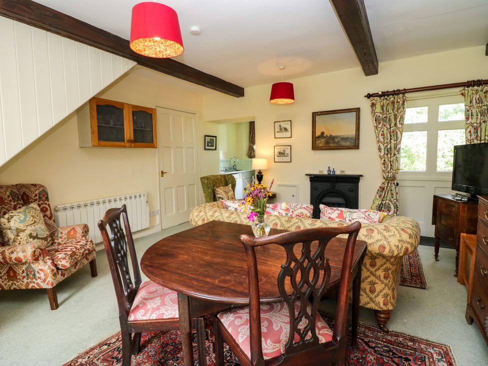 A living room with a dining table and sofa at The Gameskeepers Cottage in Cartmel