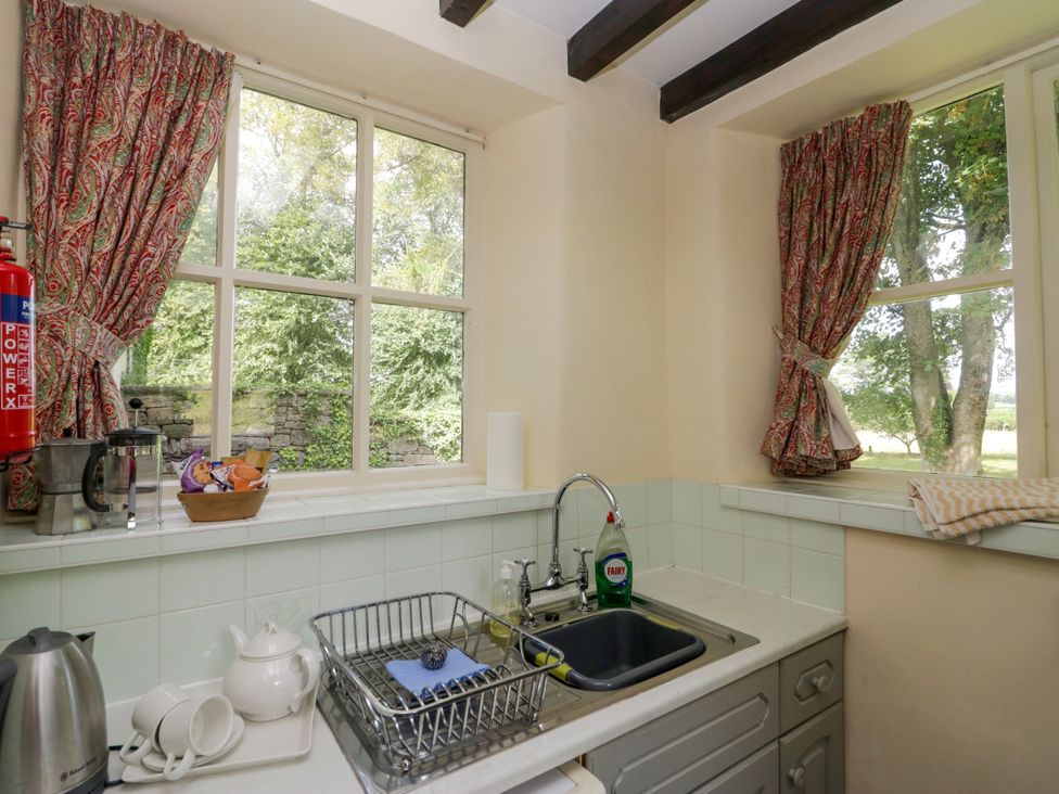 A kitchen with a sink and dish rack at The Gameskeepers Cottage in Cartmel