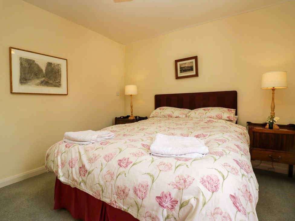 A bedroom with a bed and bedside tables at The Gameskeepers Cottage in Cartmel