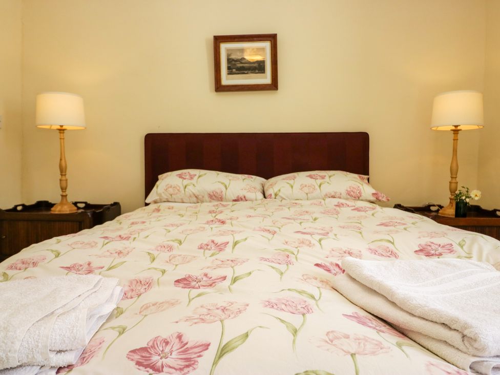 A bedroom with a bed and lamps at The Gameskeepers Cottage in Cartmel