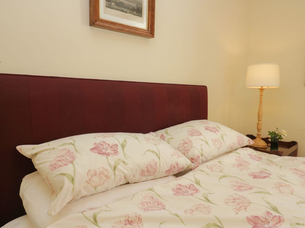 A bedroom with a bed and lamp at The Gameskeepers Cottage in Cartmel