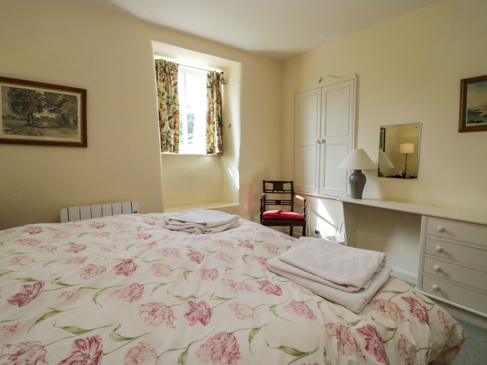 A bedroom with a bed and towels at The Gameskeepers Cottage in Cartmel