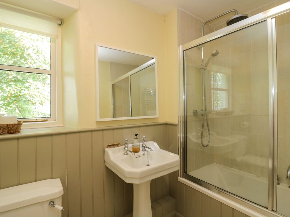 A bathroom with a shower, sink, and toilet at The Gameskeepers Cottage in Cartmel