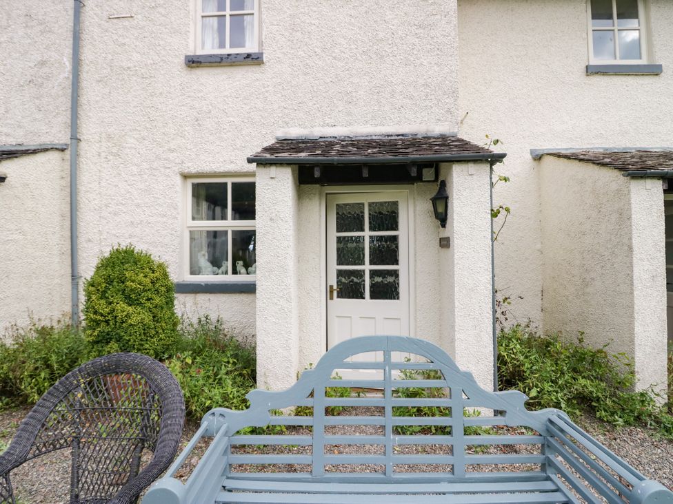 An entrance with a door and windows surrounded by greenery at The Gameskeepers Cottage in Cartmel