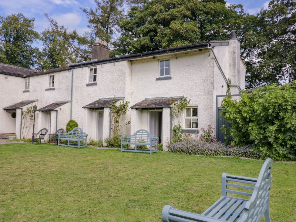 A garden with benches and a house at The Gameskeepers Cottage in Cartmel