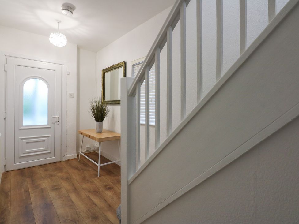 A hallway with a door, mirror, table and stairs at Tan Y Mynydd in Dwygyfylchi