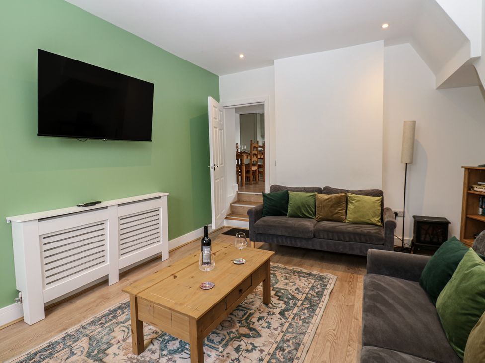 A living room with a television on the wall and a coffee table at Salvin Cottage in Alston