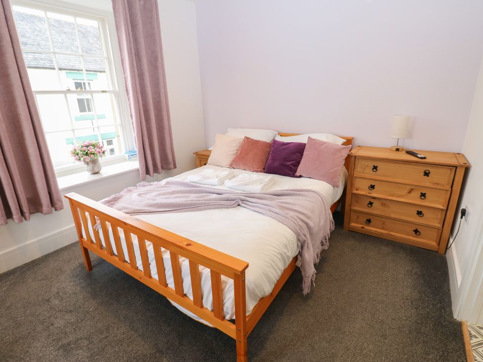 A bedroom with a bed and dressers at Salvin Cottage in Alston