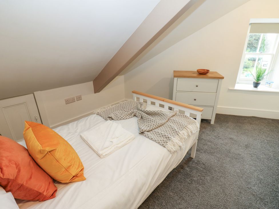 A bedroom with a bed and dresser at Salvin Cottage in Alston