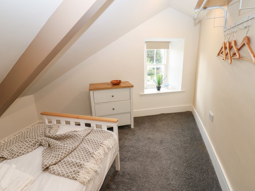 A bedroom with a bed and dresser at Salvin Cottage in Alston