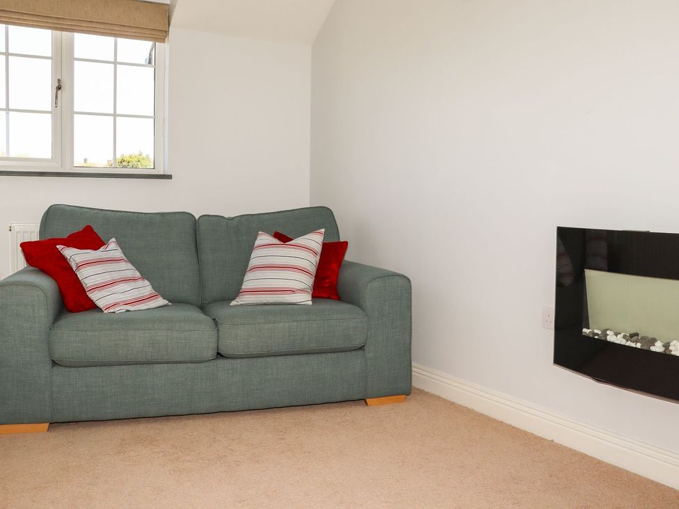 A living room with a sofa and fireplace at Atlantic View (1 bed) Bude
