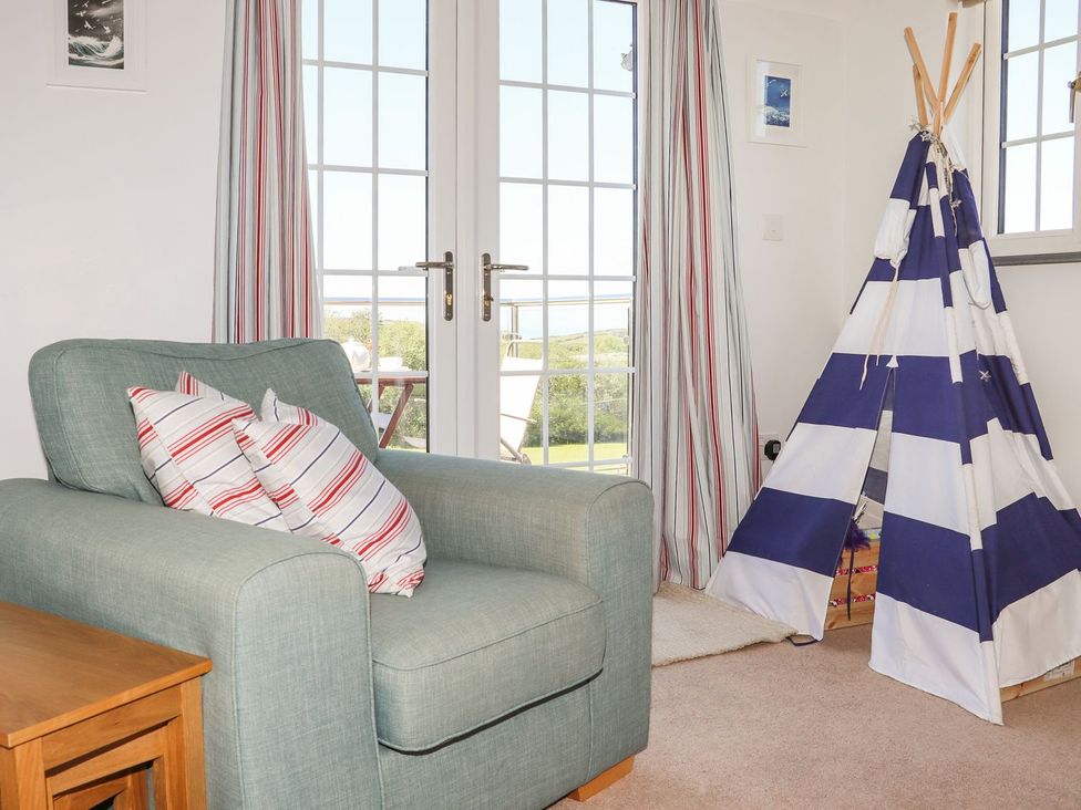 A living room with an armchair and a soft toy tent at Atlantic View (1 bed) Bude