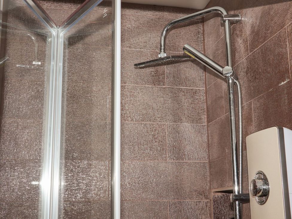 A shower with a showerhead and tiles at Atlantic View (1 bed) in Bude