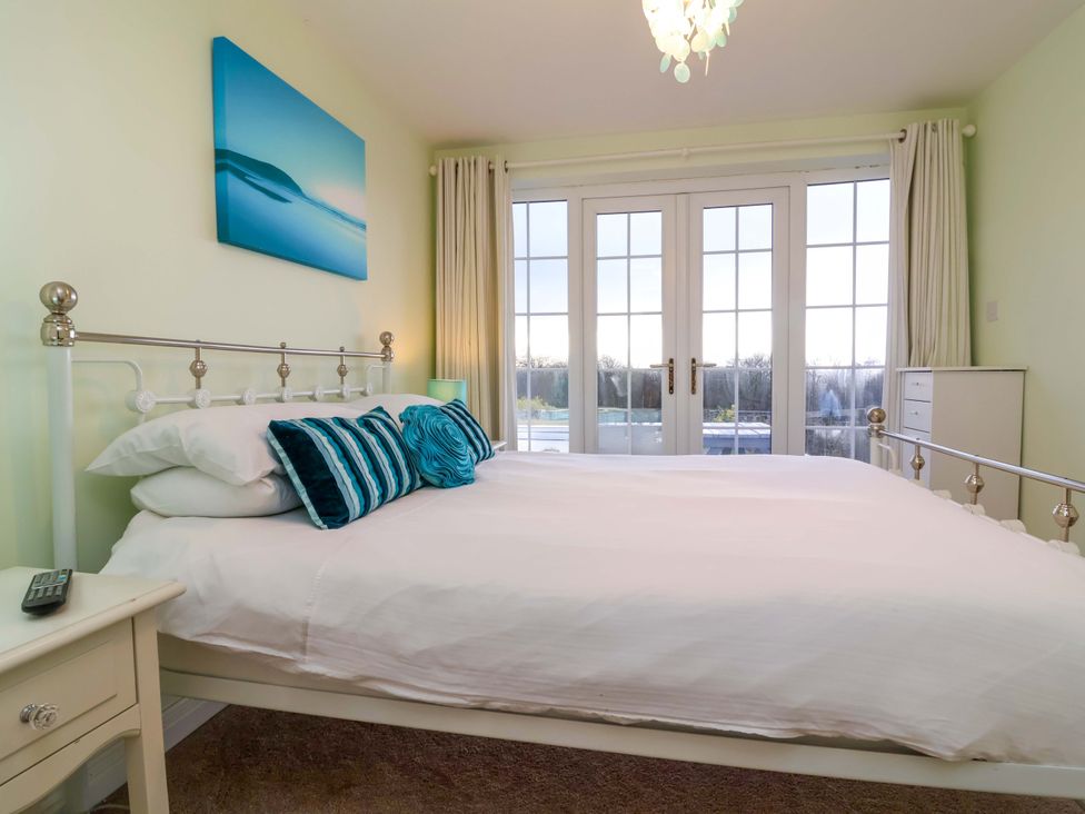 A bedroom with a bed and windows at Atlantic View Apartment Poundstock near Bude