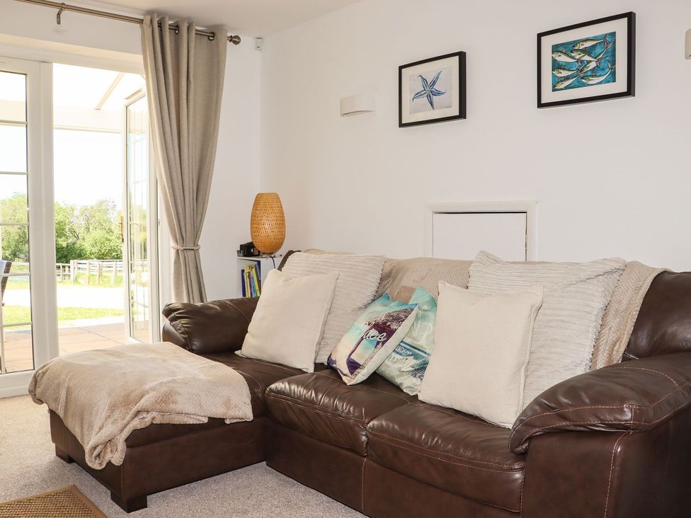 A living room with a brown sofa and sliding doors at Atlantic View (3 bed) Bude