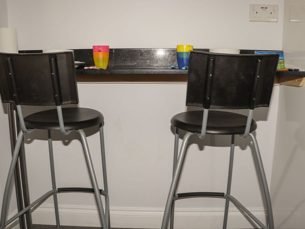 A kitchen with bar stools and cups on the countertop at Atlantic View (3 bed) Bude