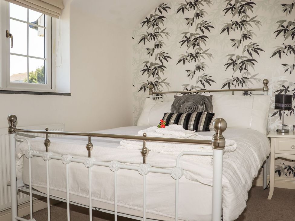 A bedroom with a bed and nightstand at Atlantic View (3 bed) Bude