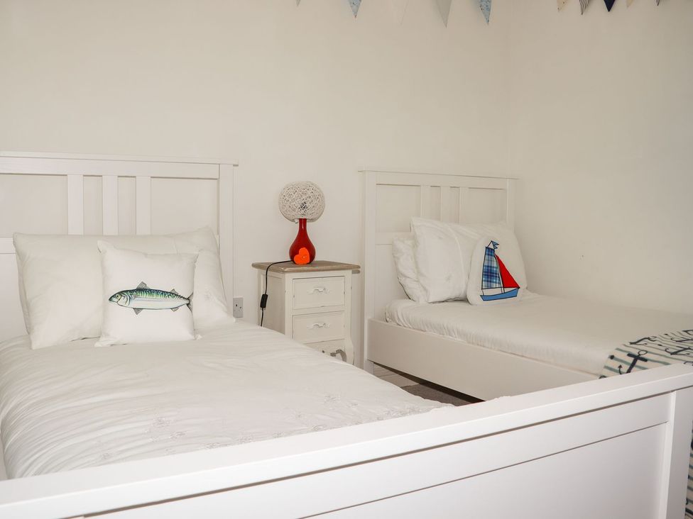 A bedroom with two beds and a lamp at Atlantic View (3 bed) in Bude