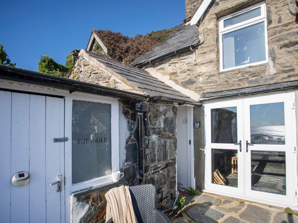 An outdoor view of The Ingle with stone walls and doors in Barmouth