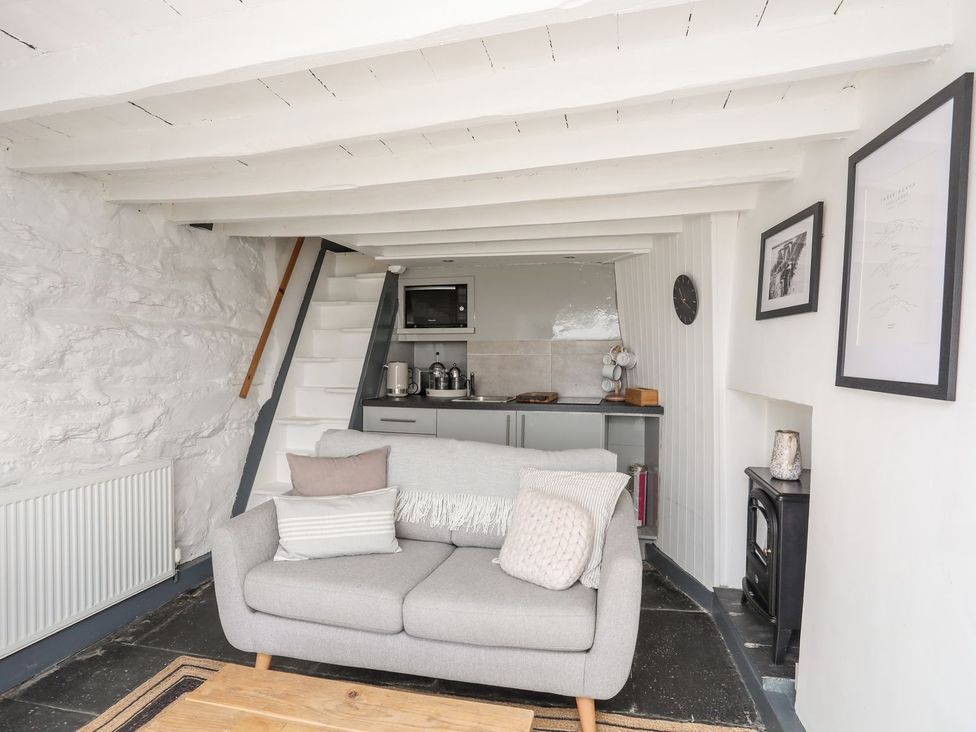 A living room with a sofa and kitchen area at The Ingle in Barmouth