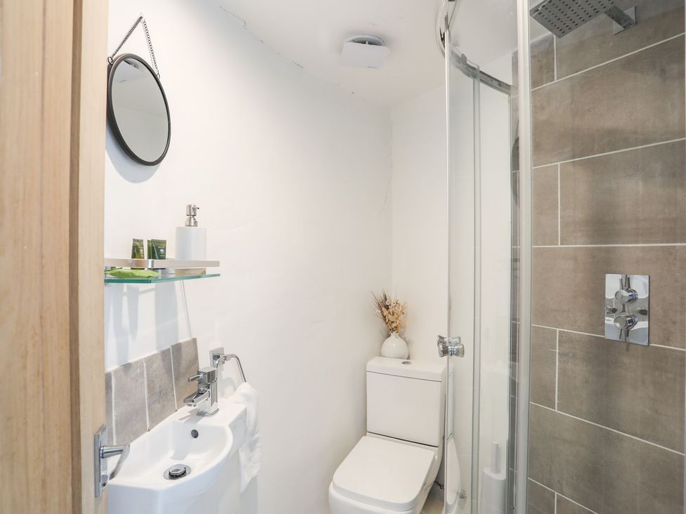 A bathroom with a sink, toilet, and shower at The Ingle in Barmouth
