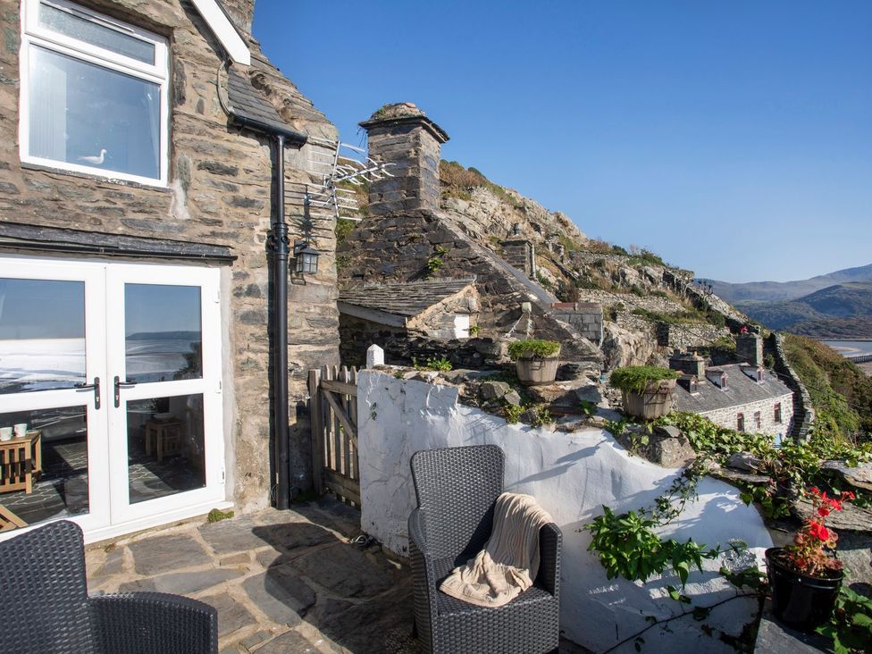 An outdoor area with a stone house and patio furniture at The Ingle in Barmouth