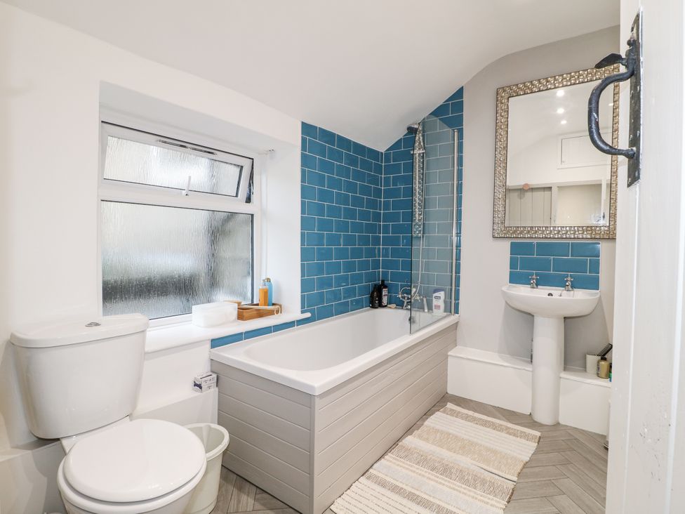 A bathroom with a bathtub, sink, and window at 5 Belper Lane End in Belper