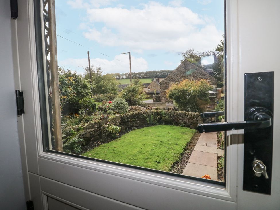 A view of a garden and house through a window at 5 Belper Lane End in Belper