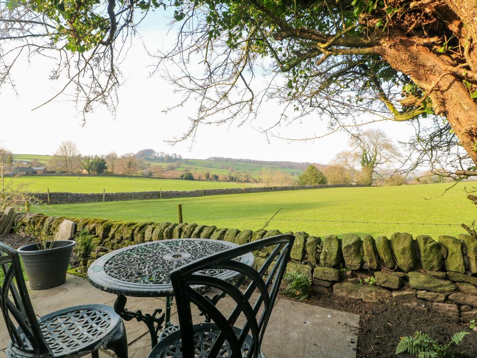 A table and chairs on a patio overlooking a grassy field and trees at 5 Belper Lane End in Belper