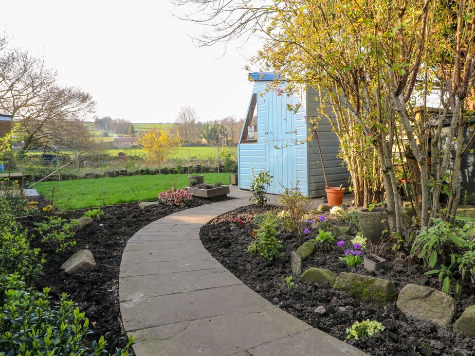 A garden with a path leading to a shed and flower beds at 5 Belper Lane End, Belper