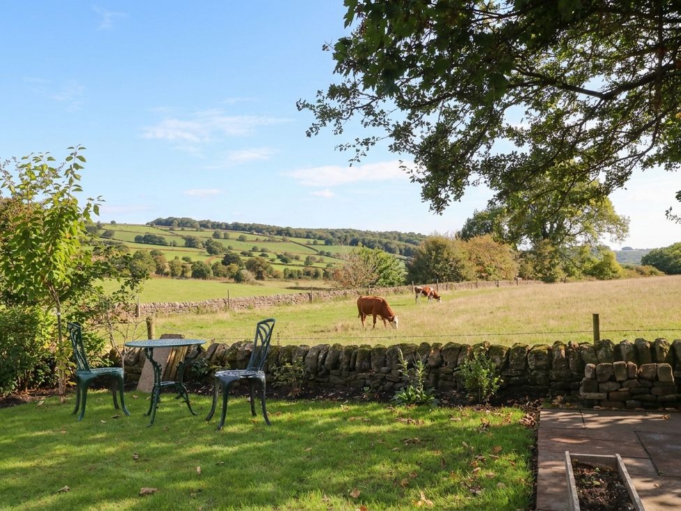 A garden with a table and chairs overlooking cows in a field at 5 Belper Lane End Belper