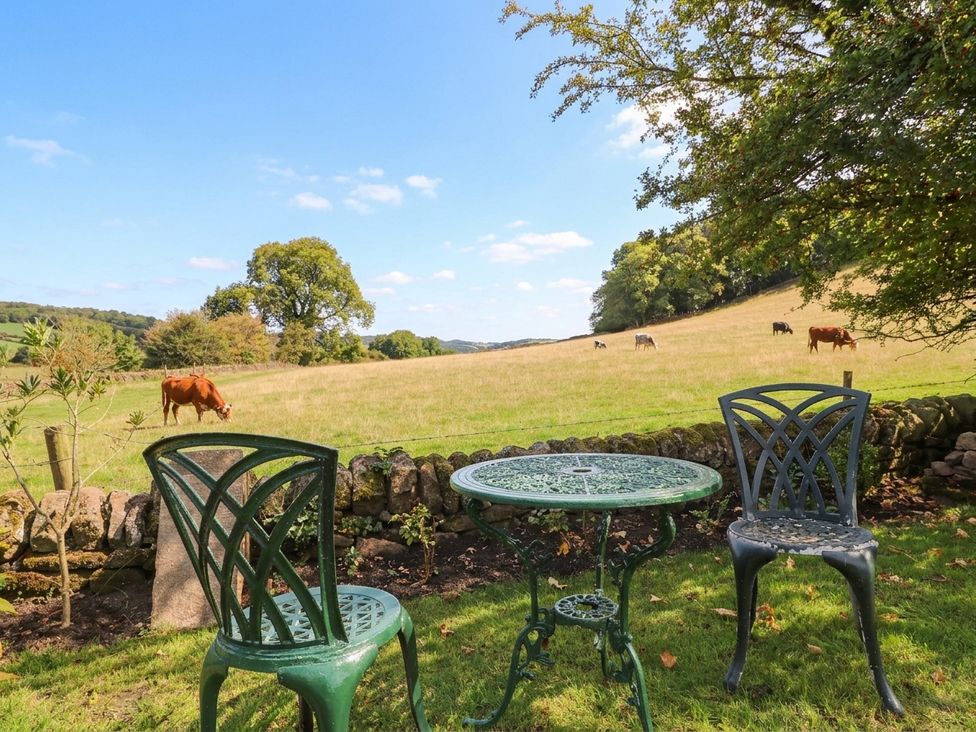 A garden with a table and chairs overlooking a field with cows at 5 Belper Lane End in Belper