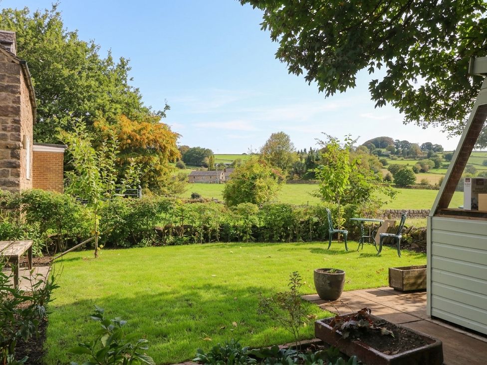 A garden with grass, trees, and chairs at 5 Belper Lane End in Belper