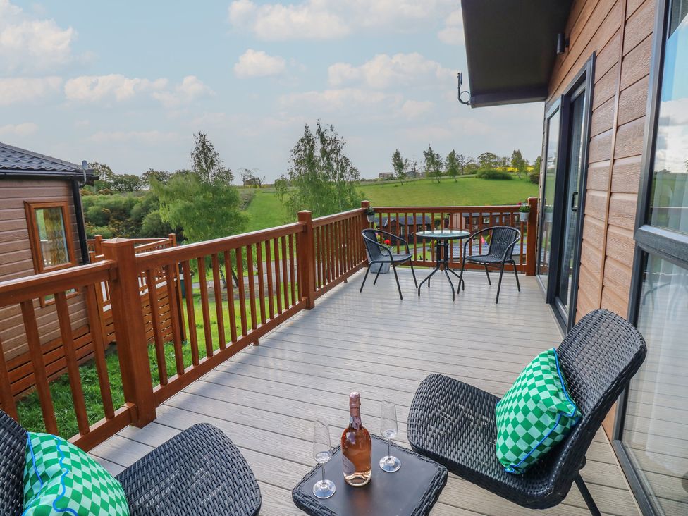 A deck with chairs and table overlooking green fields at Lodge 52 in Richmond