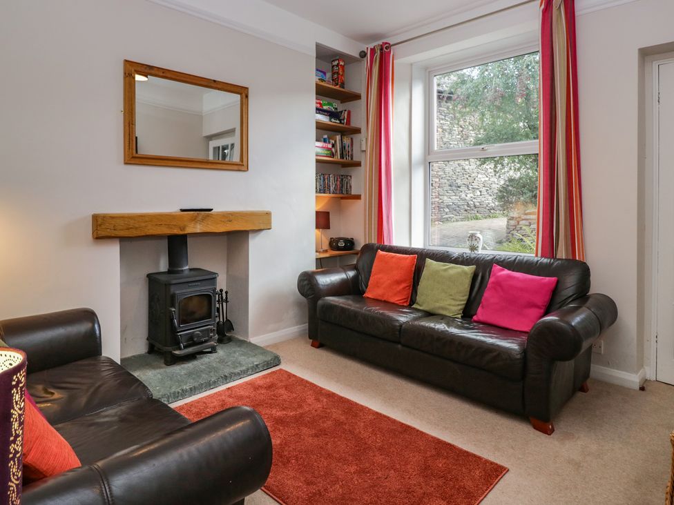A living room with a fireplace and bookshelf at Cloud Cottage in Ambleside