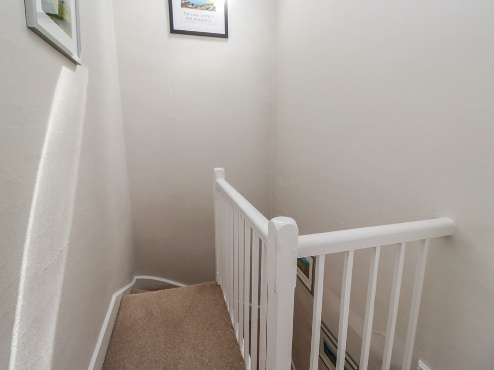 A staircase with a handrail and framed pictures at Cloud Cottage in Ambleside