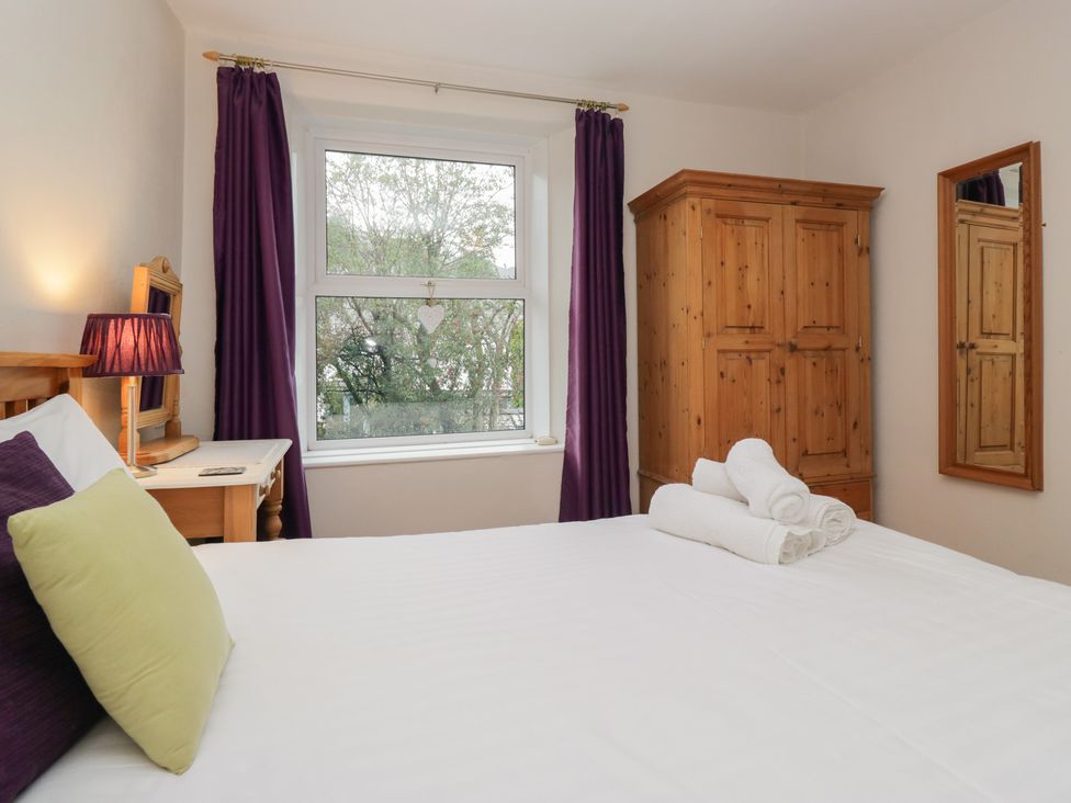 A bedroom with a bed, wardrobe, and mirror at Cloud Cottage Ambleside